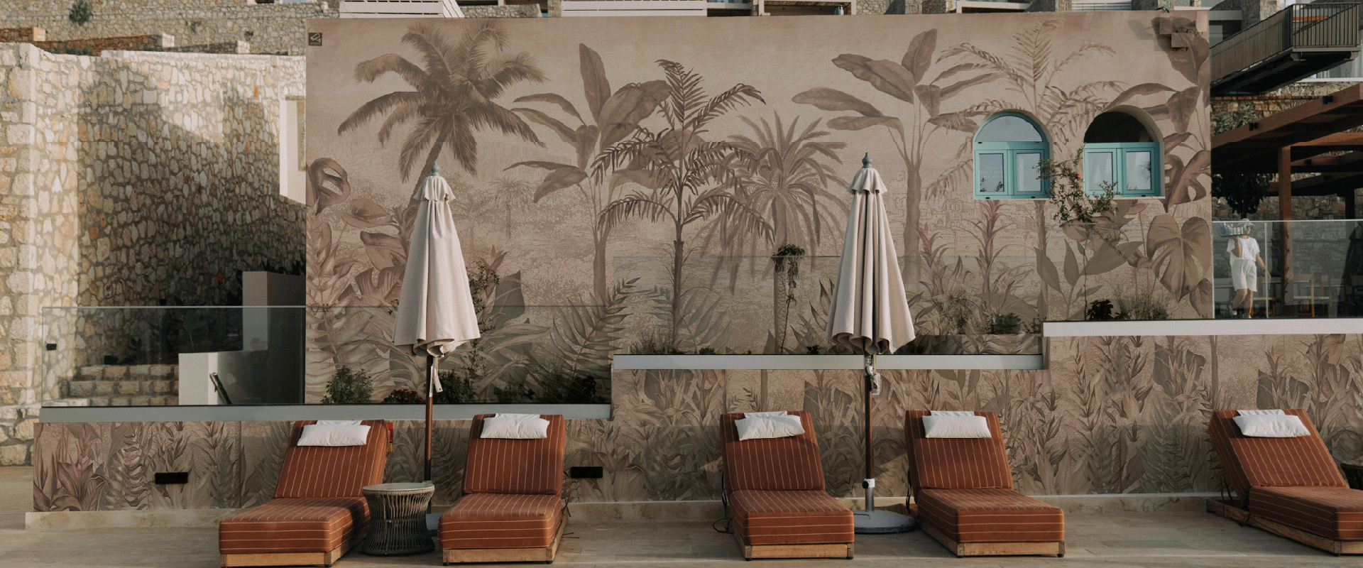 Area piscina esterna con sdraio e murale tropicale Alambra Viameucci a tema palma